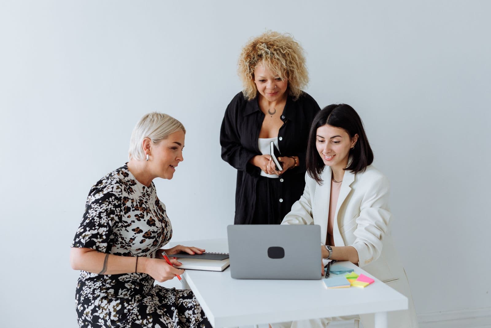 Three colleagues reviewing work together at a laptop